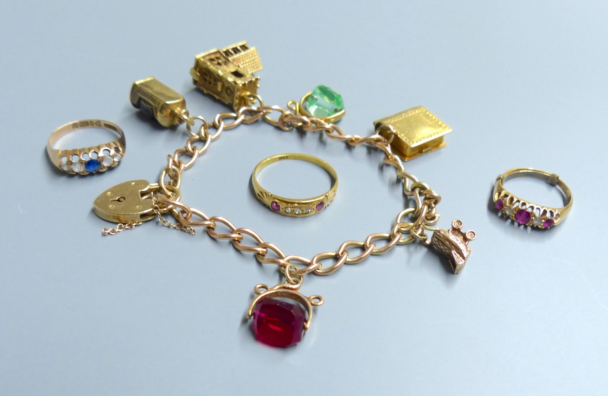 A 9ct gold charm bracelet, hung with six assorted charms including 9ct gold and 3 rings.
